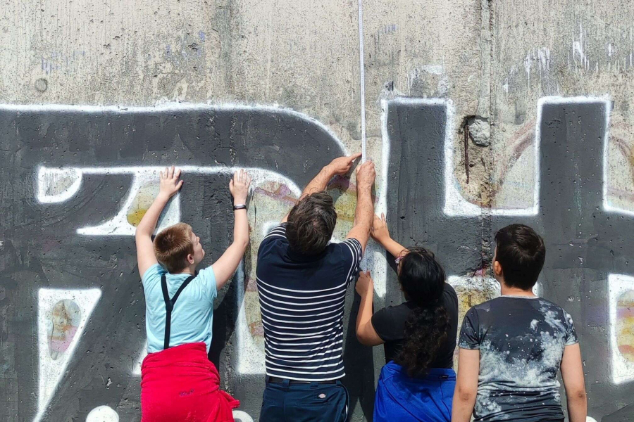Jugendgruppe misst Höhe der Mauer mit einem Zollstock