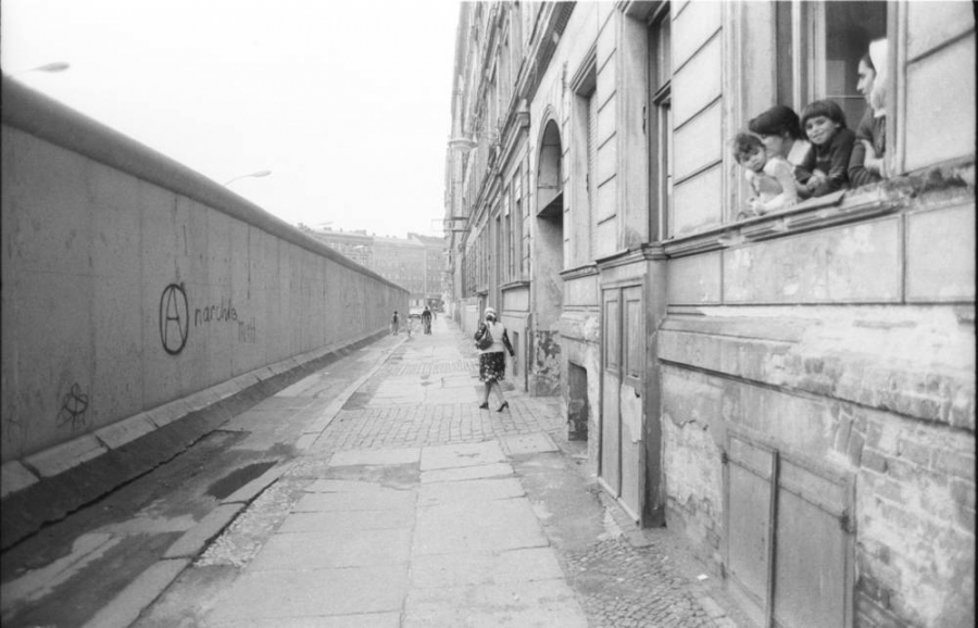 Kinder schauen aus einem Fenster eines Gebäudes an der West-Berliner-Mauer