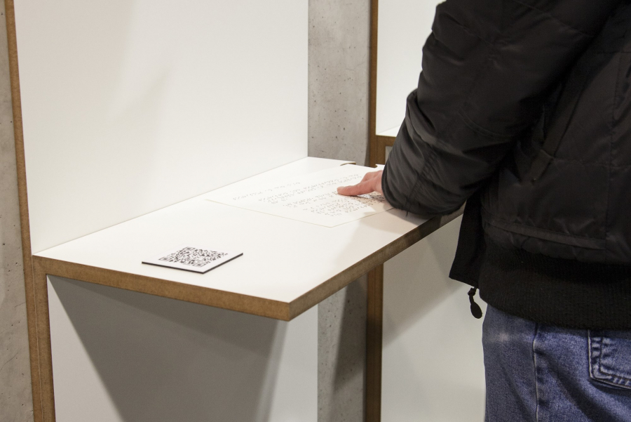 Person ertastet Brailleschrift am Ausstellungsmodul