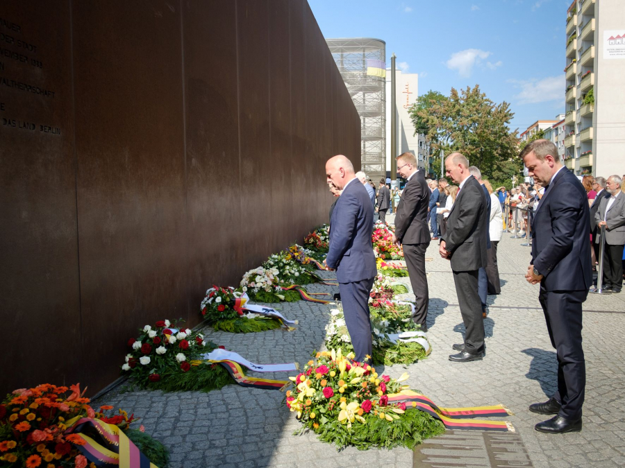 Gäste stehen vor Kränzen am Denkmal