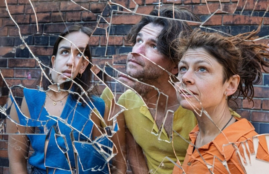 Drei Personen schauen in die Ferne hinter einer zerbrochenen Glasscheibe