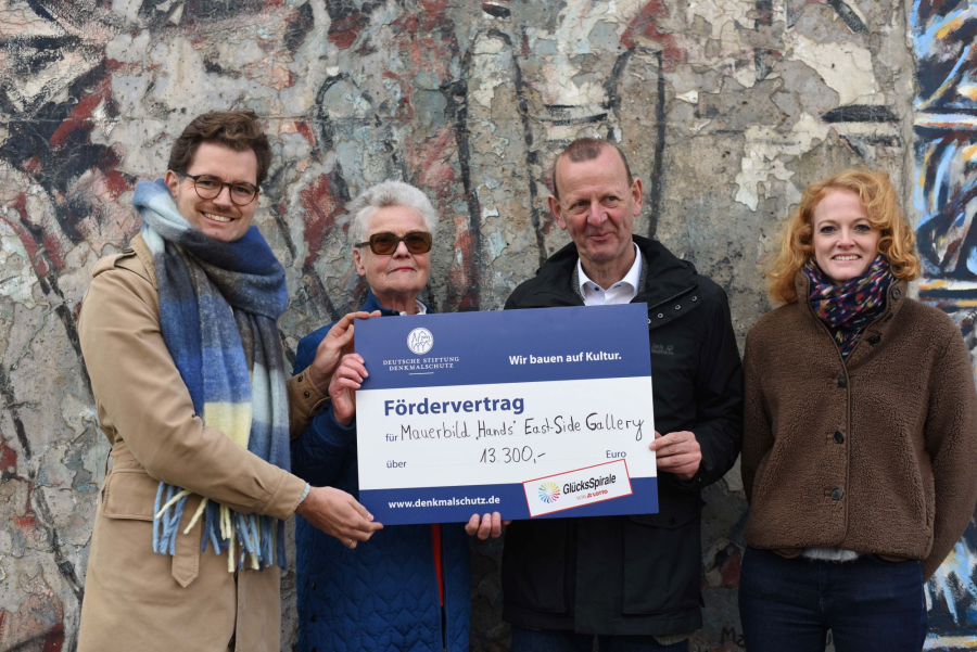 Foto von vier Personen und einem Check