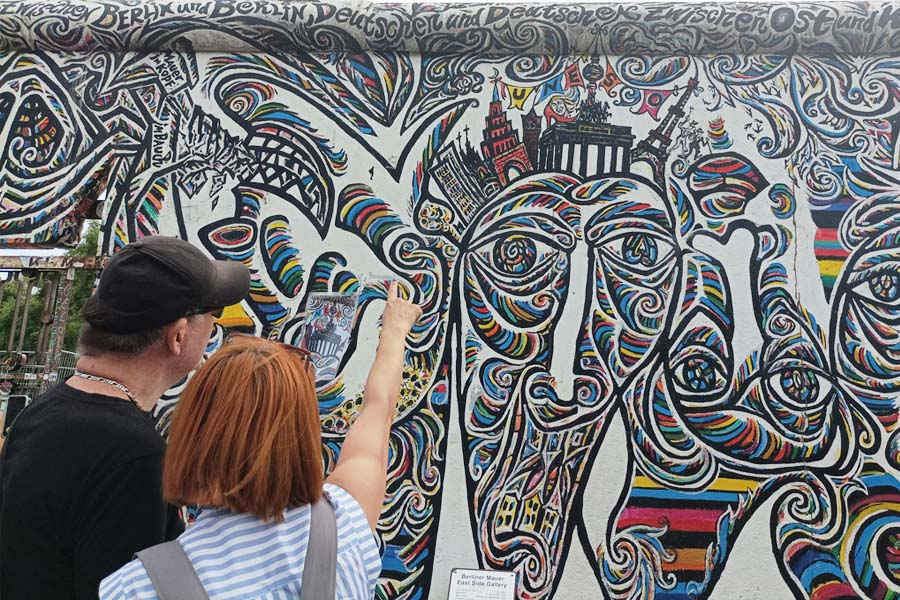 Tour in simplified language at the East Side Gallery in front of the painting World's People by Schamil Gimajew