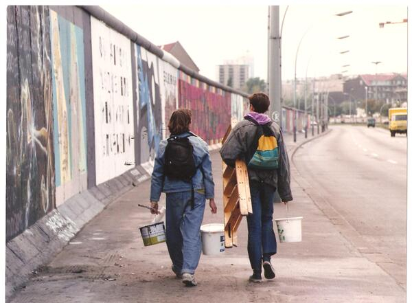 Zwei Personen laufen an der East Side Gallery entlang
