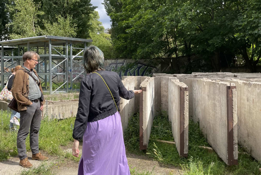 eine Person zeigt draußen auf umgefallene Mauerstücke 