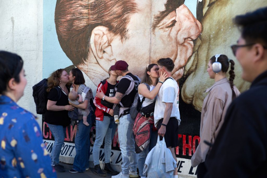 Menschen stehen vor dem Bild "Bruderkuss" an der East Side Gallery und küssen sich