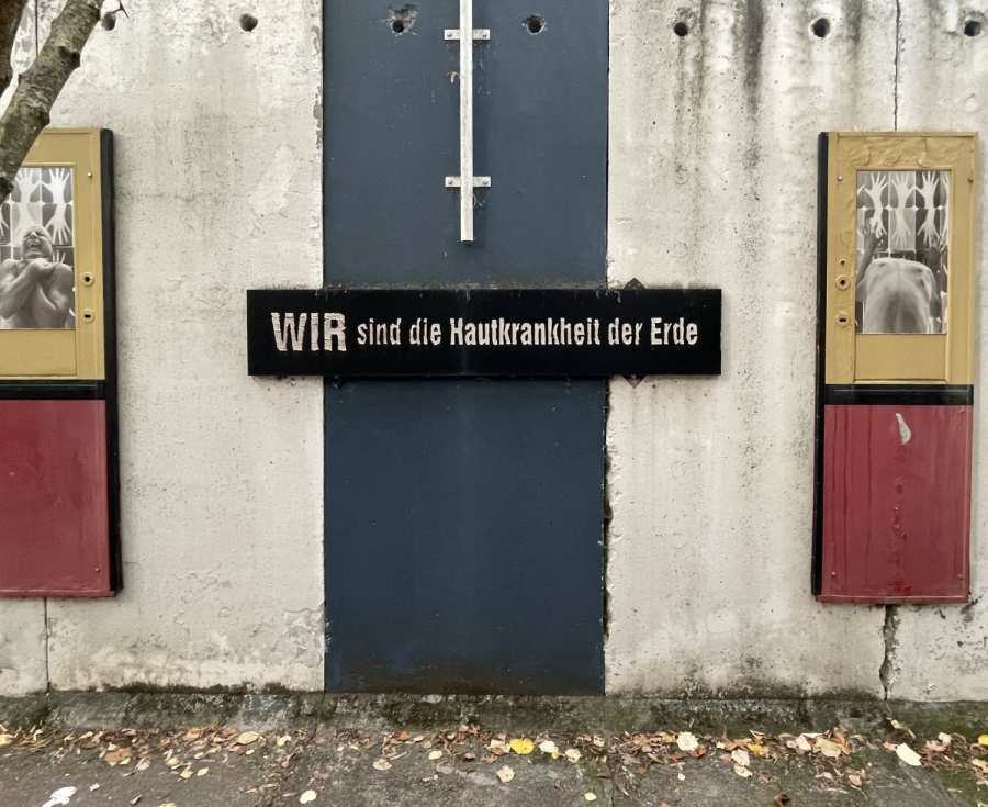 Foto vom Mauerstück im Parlament der Bäume mit dem Schriftzug "Wir sind die Hautkrankheit der Erde."