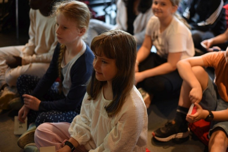 Kinder sitzen auf dem Boden und schauen nach vorne