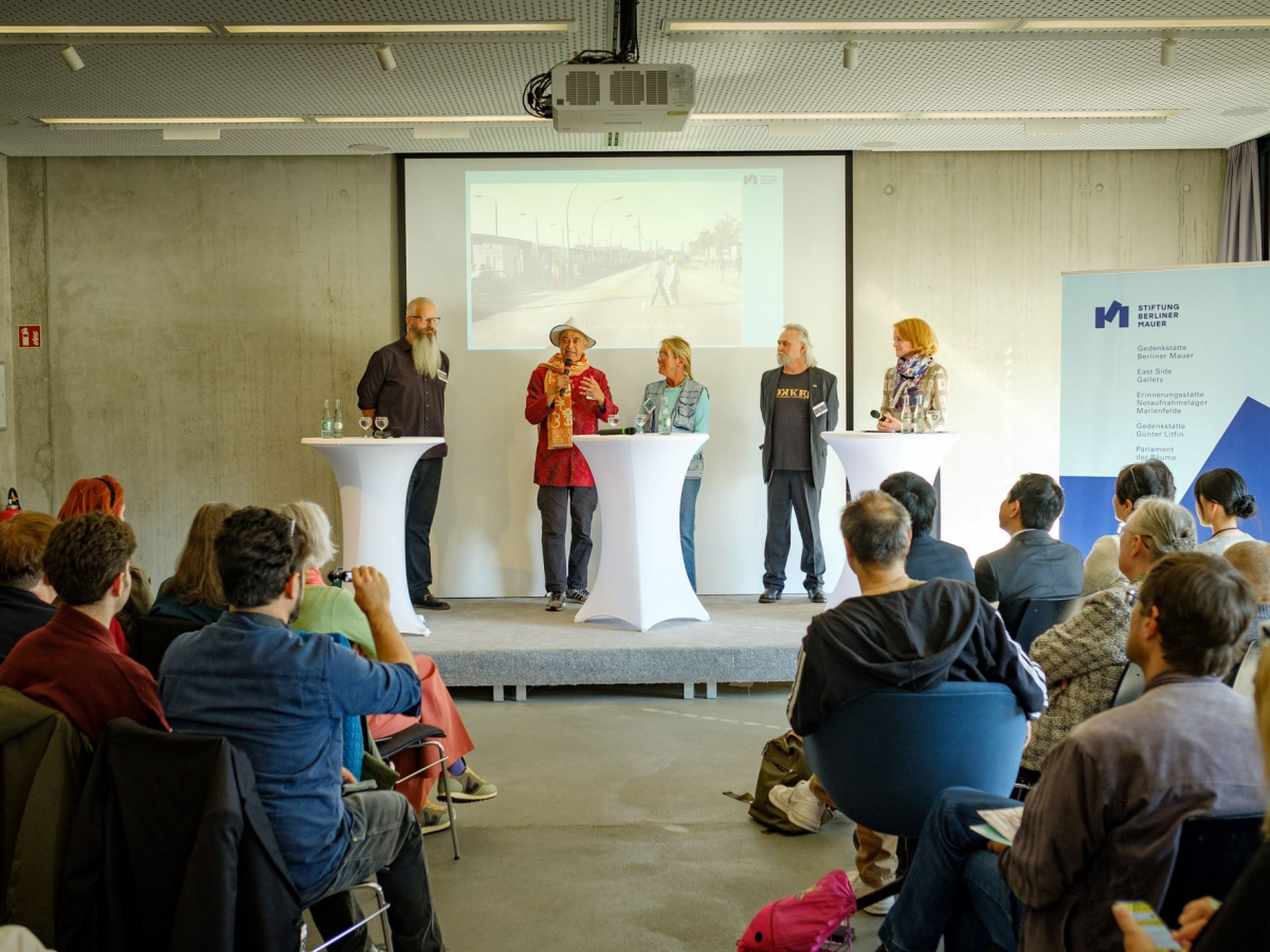 Personen stehen in einem Innenraum auf der Bühne
