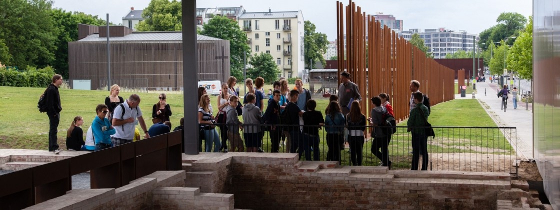 Menschengruppe schaut sich ein archäologisches Fenster in der Außenausstellung an