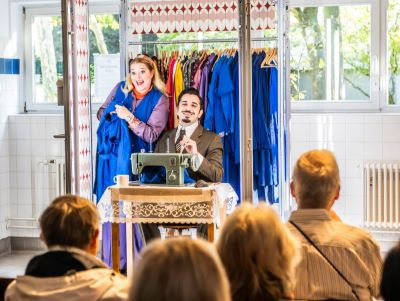 Zwei Schauspieler auf einer kleinen Bühne mit Nähmaschine