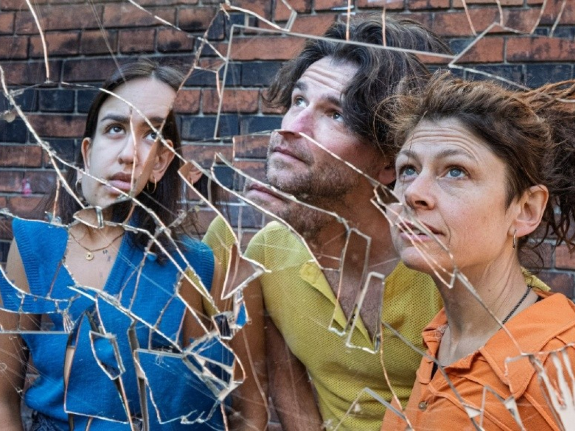 Drei Personen schauen in die Ferne hinter einer zerbrochenen Glasscheibe