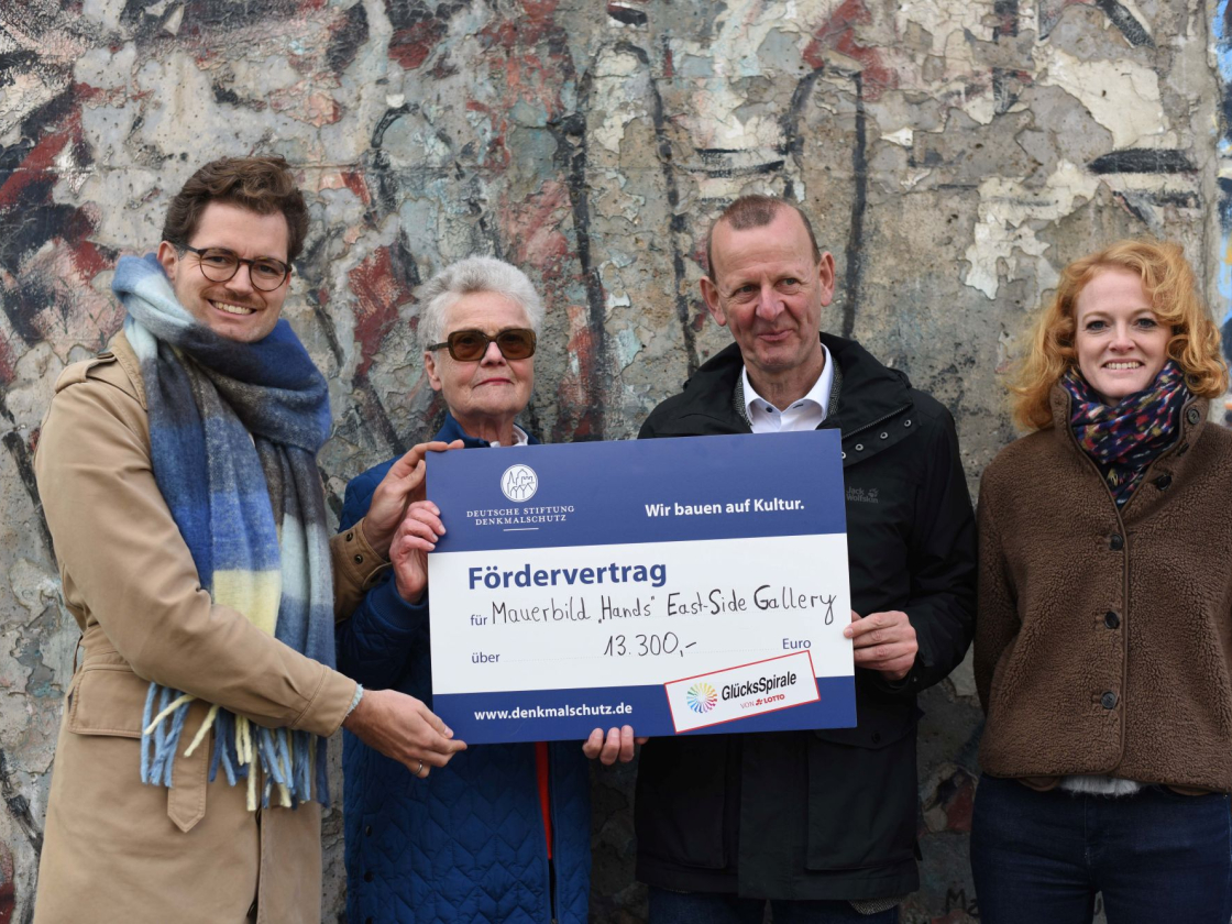 Foto von vier Personen und einem Check