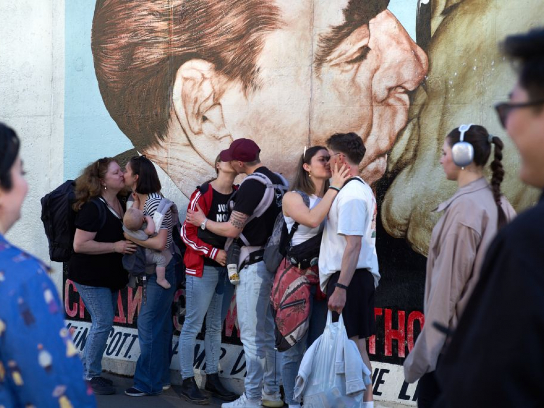 Menschen stehen vor dem Bild "Bruderkuss" an der East Side Gallery und küssen sich
