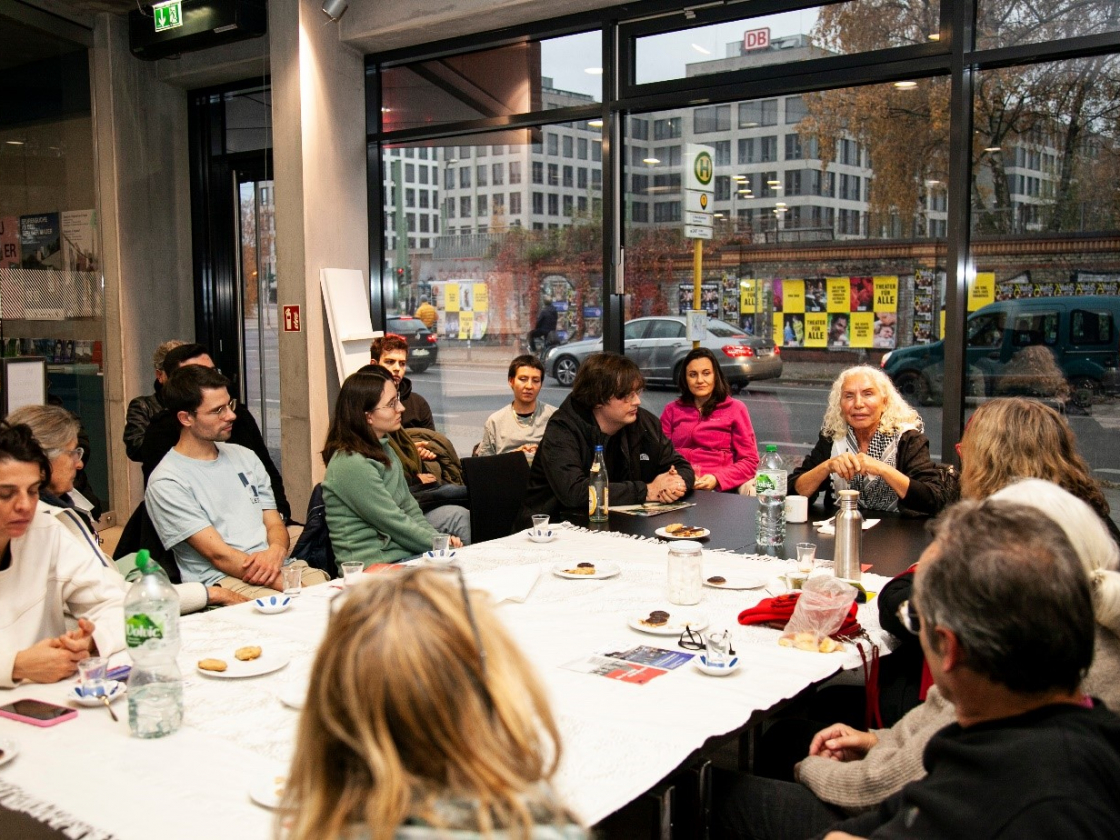 Personen sitzen an einem großen Tisch und sprechen miteinander