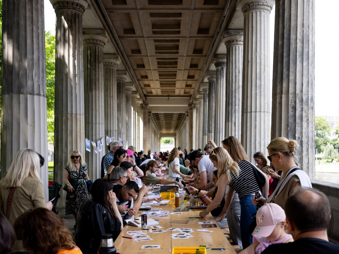 Personen sitzen an einer Tafel unter dem Kolonnadenhof der Museumsinsel