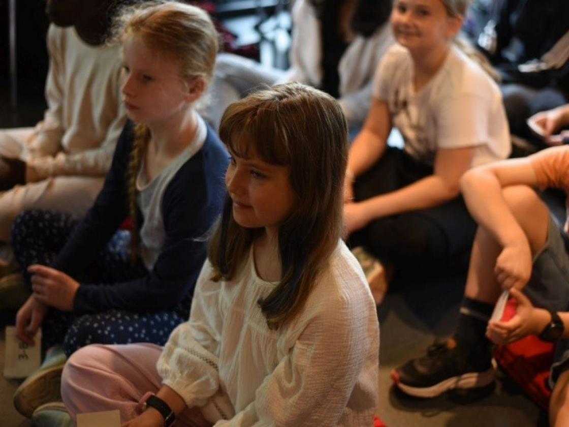 Kinder sitzen auf dem Boden und schauen nach vorne