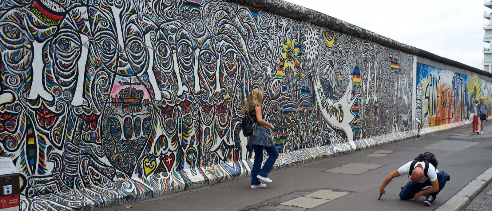 Eine Frau wird von einem Mann vor der East Side Gallery fotografiert