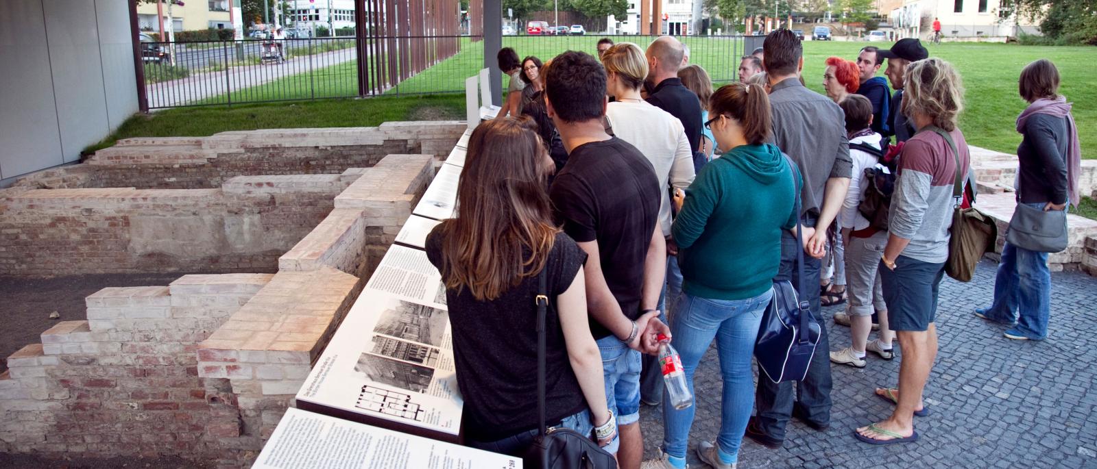 A group of visitors at the Berlin Wall Memorial inspects the remains of the border house