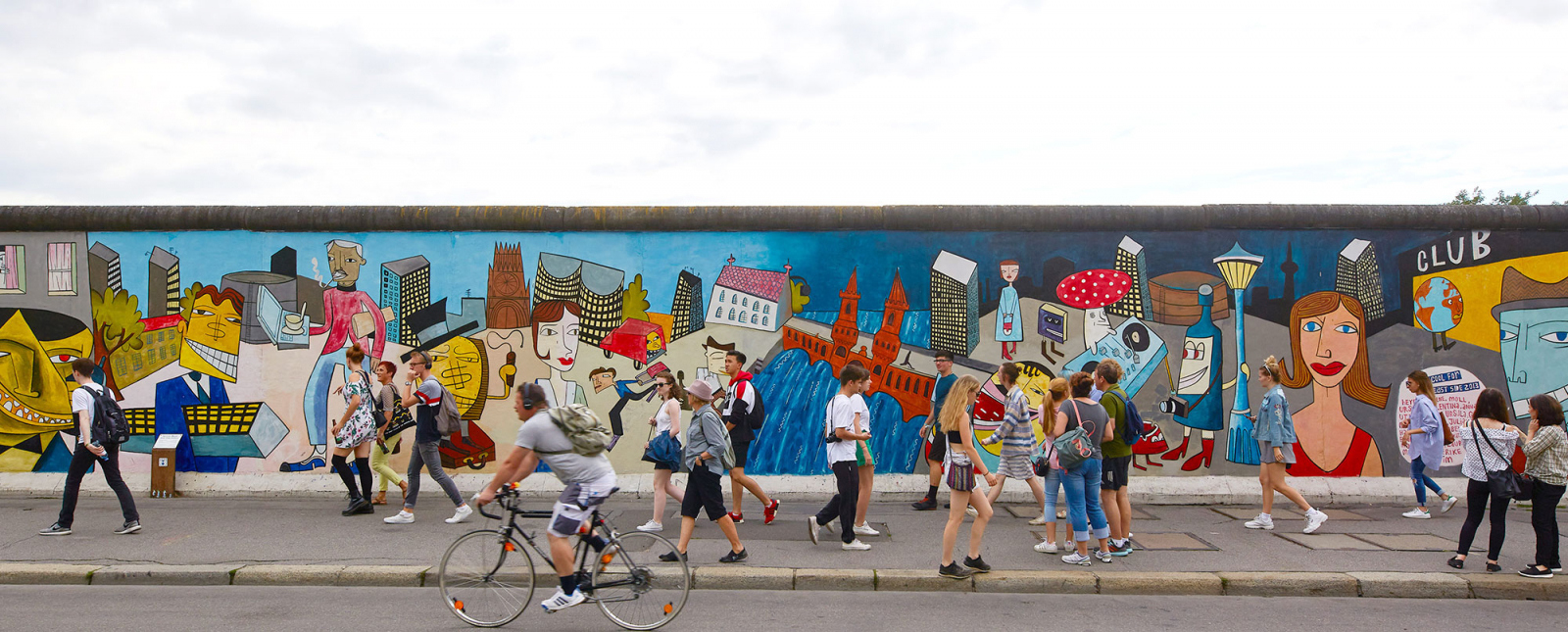 Personen spazieren und fahren entlang der East Side Gallery