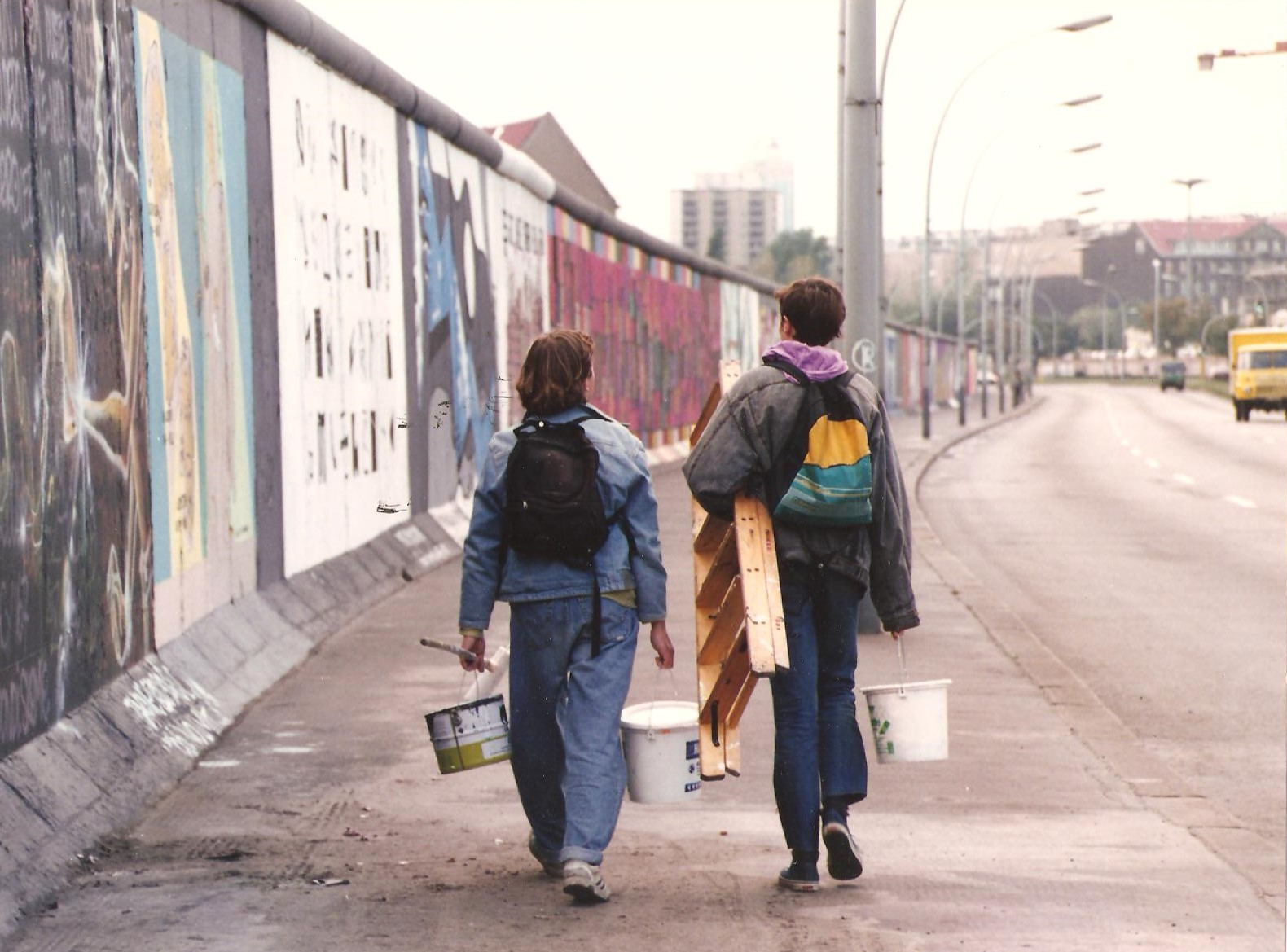 Personen mit Malwerkzeug laufen entlang der East Side Gallery